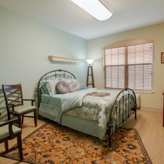 A cozy and well-lit bedroom featuring a decorative bed, comfortable chairs, and a warm color palette.
