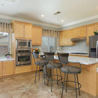 A modern kitchen featuring wooden cabinets, sleek appliances, and bar seating.