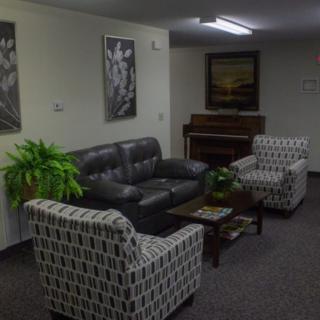 A cozy living room with a couch, armchairs, and a piano.