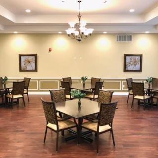 A spacious dining room with neatly arranged tables and chairs, adorned with elegant lighting and decor.
