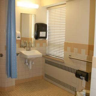 A clean and well-lit bathroom with a sink, mirror, and window with blinds.