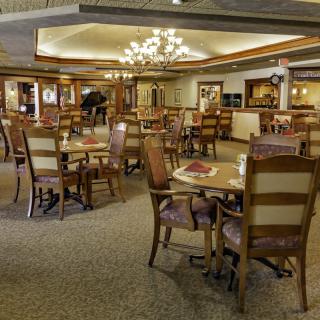 Elegant restaurant dining area with tables, chairs, and a central chandelier.