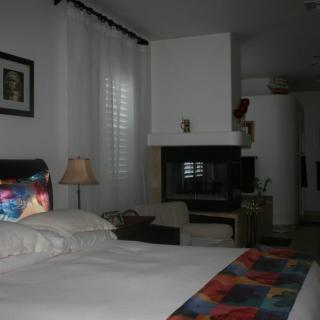 A cozy bedroom featuring a bed with colorful accents and a fireplace.