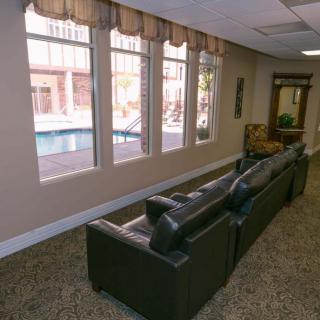 A cozy lobby area with comfortable couches and large windows offering a view of the pool outside.
