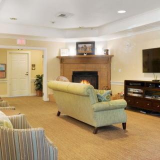 A cozy living room interior featuring a green sofa, a fireplace, and a television.