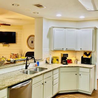 A modern kitchen with white cabinets and a granite countertop, featuring a sink and various appliances.