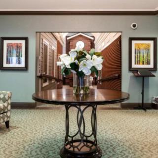 A decorated lobby area featuring a round table with floral arrangements and framed artwork on the walls.