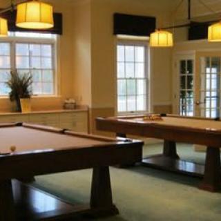 A well-lit game room featuring two pool tables and large windows.