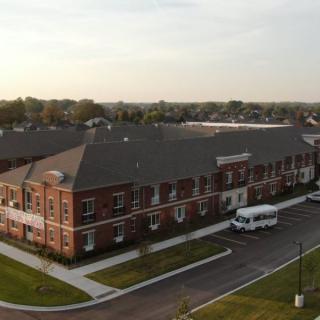 Aerial view of a residential building during sunset with a road and vehicle nearby.
