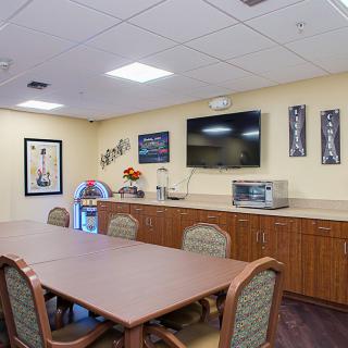 A conference room setup with a long table, chairs, and amenities such as a television and microwave.