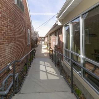 A narrow alleyway with railings leading between two brick and beige buildings.