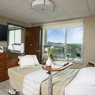A clean and comfortable hospital room with a bed near a large window.