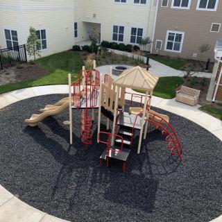 A colorful playground in an apartment complex courtyard, featuring slides and climbing structures.