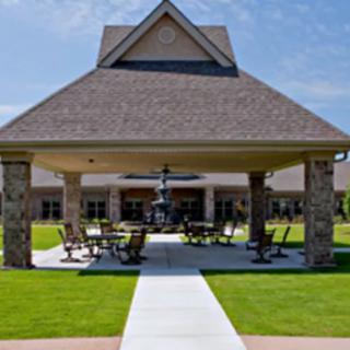 A pavilion with stone columns and outdoor seating on a sunny day.