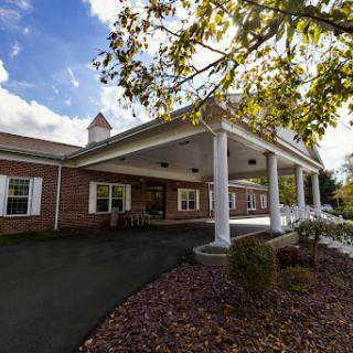 A welcoming residential building with a spacious porch, surrounded by nature.