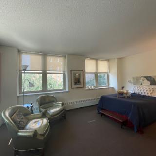 A bright and spacious living room featuring two elegant chairs, large windows, and a table setup.