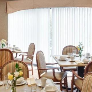 A well-arranged dining room with tables set for a meal, featuring elegant chairs and floral decorations.