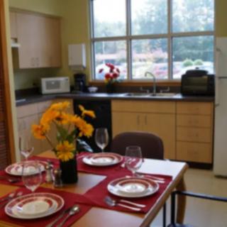 A cozy kitchen with a dining table set for a meal, adorned with flowers.