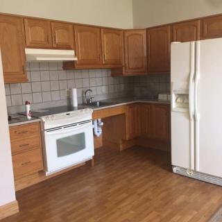A kitchen featuring wooden cabinets, a refrigerator, and a stove with wood flooring.