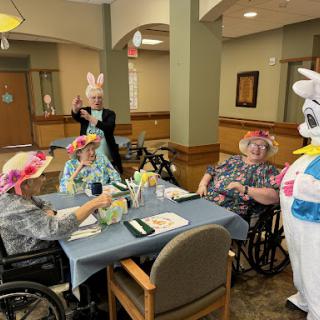 Seniors enjoying an Easter celebration with a bunny mascot at their community center.