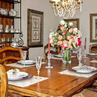 An elegantly set dining table with a floral centerpiece and crystal chandelier.