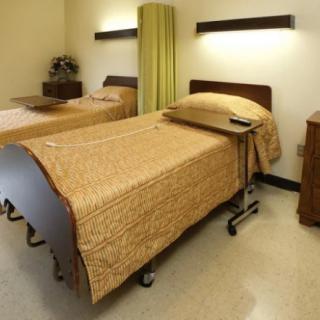 A hospital room with two beds and privacy curtains.