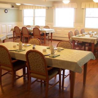 A neatly arranged dining room with tables set and chairs placed around them.