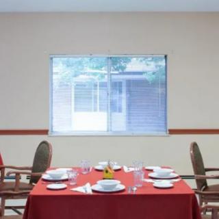 A neatly set dining table with a red tablecloth in a bright room.