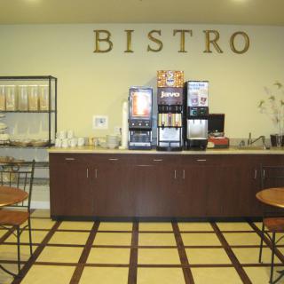Interior of a bistro featuring a coffee station with beverage dispensers and seating area.