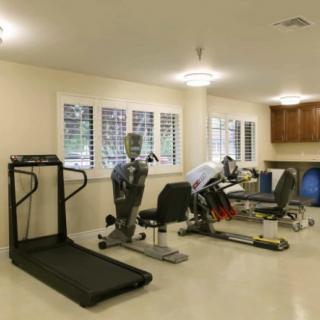 A well-equipped gym room with various exercise machines, including a treadmill and stationary bikes.