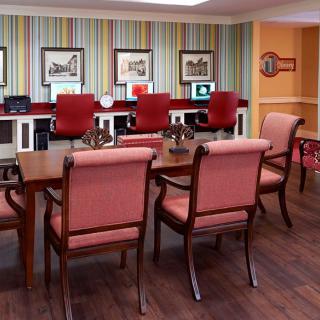 A well-decorated conference room featuring a large wooden table, upholstered chairs, and framed artwork on the walls.