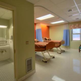 A well-lit hospital room with two patient beds and a private bathroom.