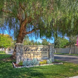 An entrance sign for Desert Hills Ranch Estates surrounded by lush greenery and trees.