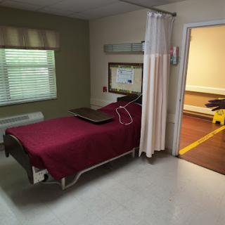 A patient room in a hospital with a bed, curtain, and a view of the outside.