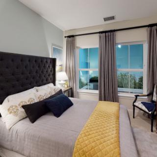 A stylish bedroom with modern decor, featuring a large bed, a window with curtains, and a cozy ambiance.