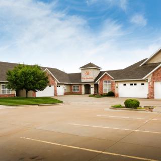 A spacious residential building with multiple garages and a tree in the front yard.
