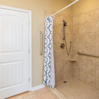A tiled bathroom with a shower area featuring a patterned curtain and grab bars for accessibility.