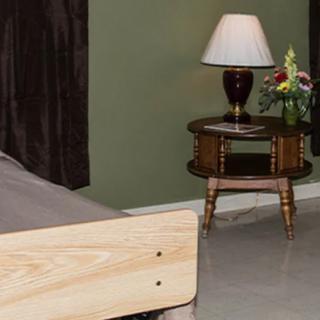 A cozy bedroom corner featuring a wooden nightstand with a lamp and a bouquet of flowers.