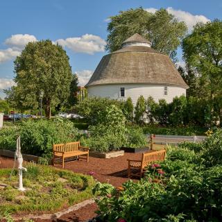 A tranquil garden with benches and a large domed building under a clear blue sky.