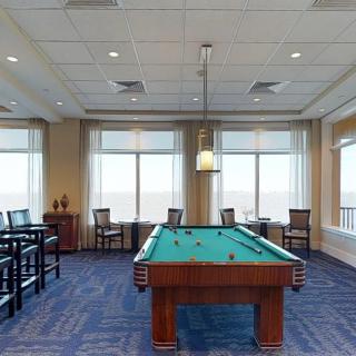 A spacious game room featuring a pool table with ample seating and large windows.