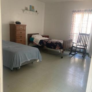 A simple bedroom with two beds, a dresser, and a rocking chair near the window.