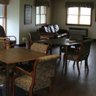 A cozy living room with multiple tables and chairs arranged near the windows.