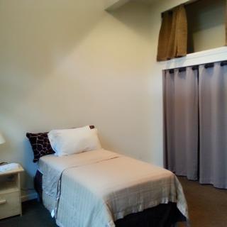 A minimalist bedroom with a single bed and neutral decor.