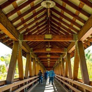People walking across a wooden covered bridge.