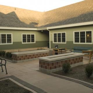 A quiet courtyard with benches, chairs, and a surrounding building exterior.