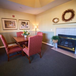 Cozy living room with a dining set and fireplace, decorated with artwork and a wreath.