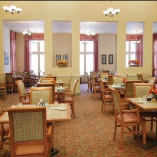 An elegantly furnished dining area with neatly arranged tables and chairs, basking in ample natural light.