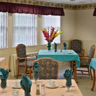 An elegantly set dining room with neatly arranged tables, featuring colorful floral centerpieces and coordinated table linens.