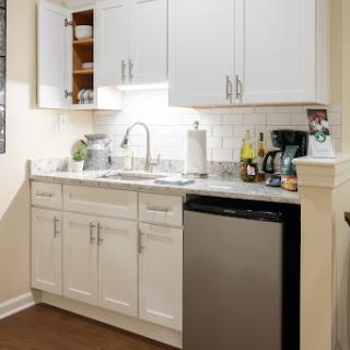 A modern kitchen featuring white cabinetry, a sleek sink, and a stainless steel dishwasher.