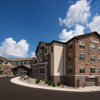 A modern apartment complex with a stone facade under a partly cloudy sky.